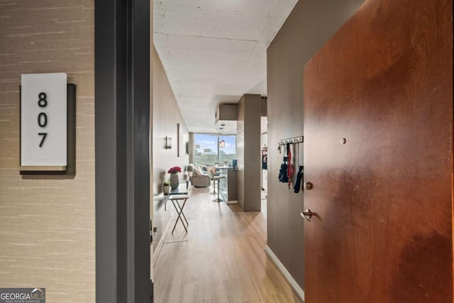 corridor with a wall of windows, wood finished floors, and baseboards