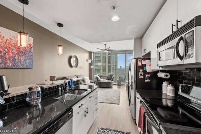 kitchen with stainless steel appliances, a sink, white cabinets, light wood-style floors, and tasteful backsplash