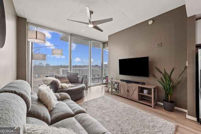 living area with expansive windows, baseboards, ceiling fan, and light wood finished floors