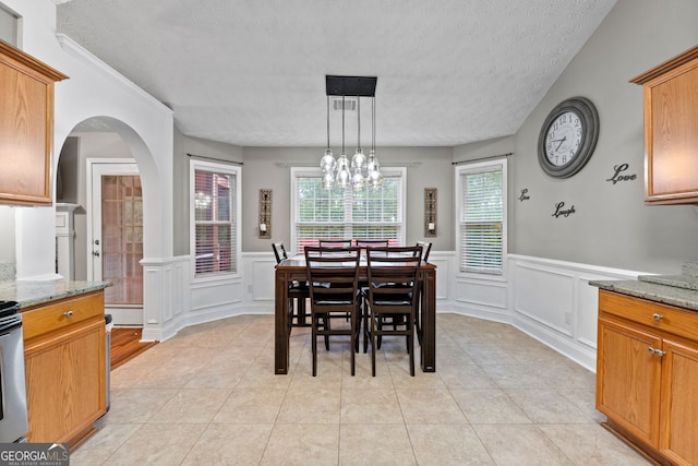 dining space featuring arched walkways, light tile patterned floors, baseboard heating, wainscoting, and a textured ceiling