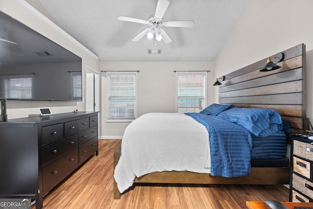 bedroom with light wood-type flooring, ceiling fan, visible vents, and vaulted ceiling