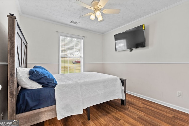 bedroom featuring visible vents, a textured ceiling, ornamental molding, and wood finished floors