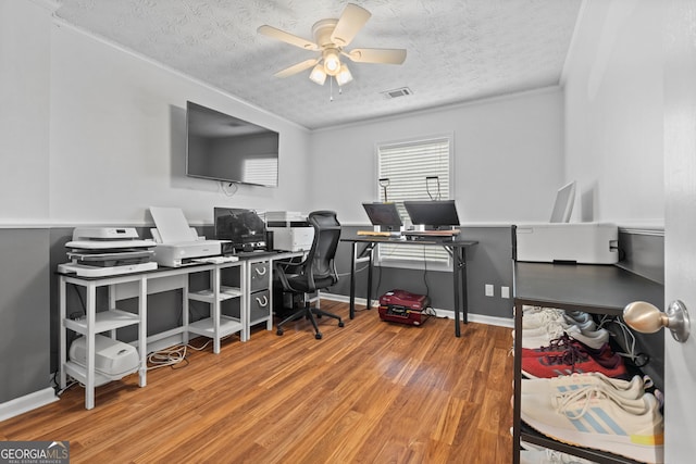 office area featuring a ceiling fan, visible vents, a textured ceiling, and wood finished floors