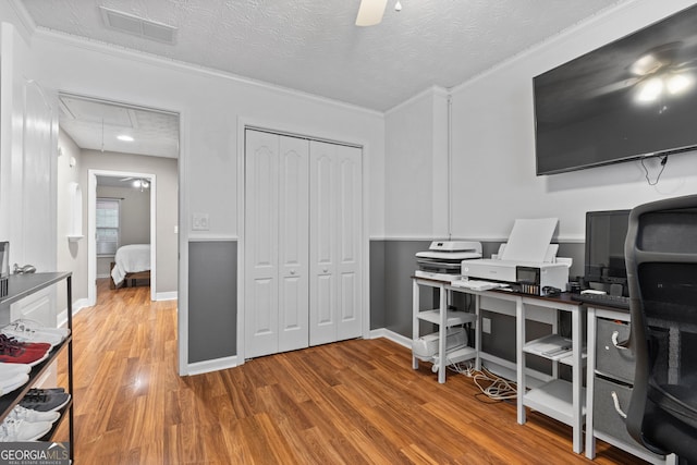 office featuring visible vents, a textured ceiling, wood finished floors, and attic access