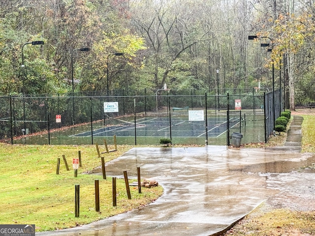 view of basketball court featuring a tennis court, community basketball court, fence, and a lawn