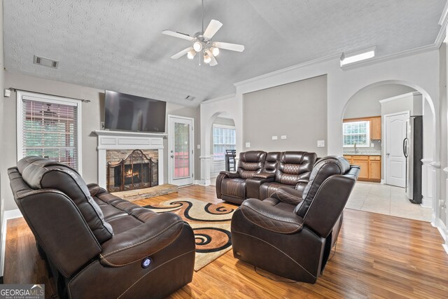 living area with light wood-type flooring, visible vents, and a stone fireplace