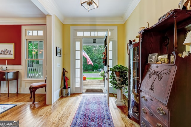 foyer entrance featuring light wood finished floors, crown molding, baseboards, and a wealth of natural light