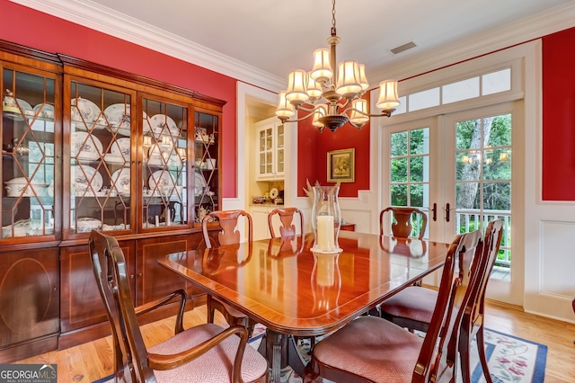 dining area featuring visible vents, light wood-style floors, french doors, ornamental molding, and an inviting chandelier