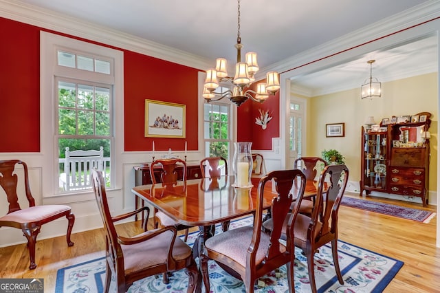 dining area with ornamental molding, wainscoting, wood finished floors, and a notable chandelier