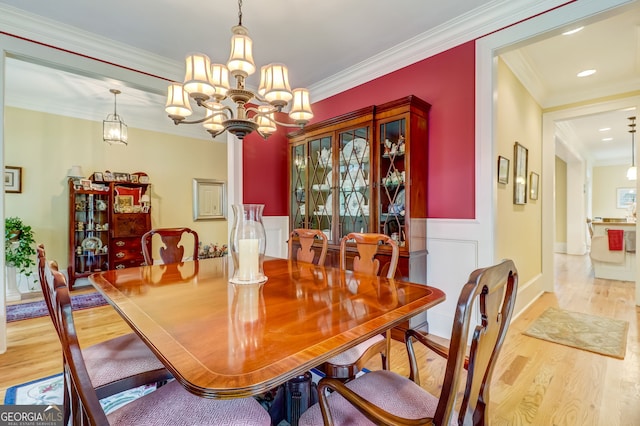 dining room with a notable chandelier, crown molding, and wood finished floors