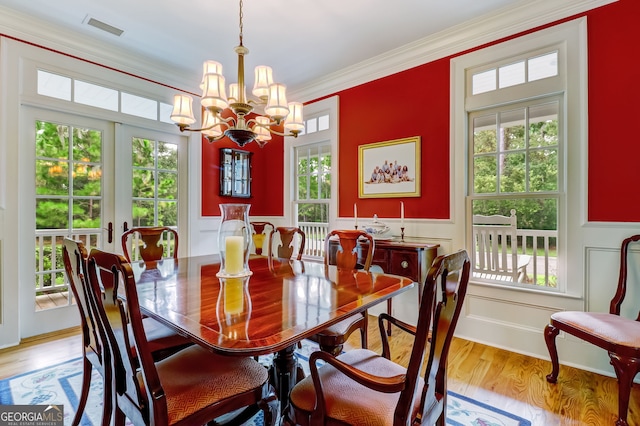 dining space with visible vents, an inviting chandelier, light wood-style floors, ornamental molding, and baseboards