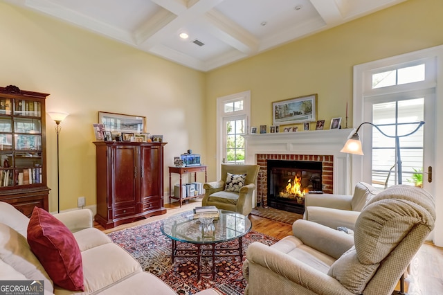 living room with coffered ceiling, a towering ceiling, wood finished floors, a fireplace, and beam ceiling