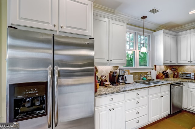 kitchen featuring a sink, white cabinets, tasteful backsplash, stainless steel fridge, and pendant lighting