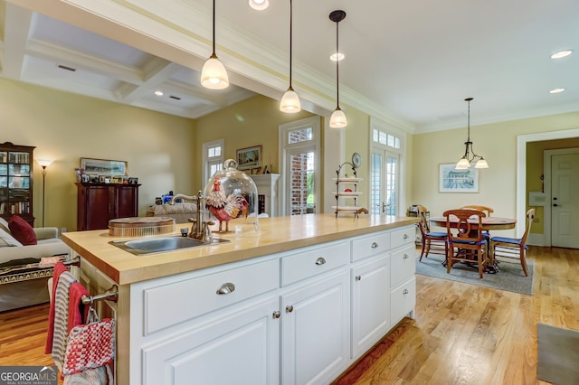 kitchen featuring light wood finished floors, open floor plan, white cabinetry, a sink, and butcher block countertops