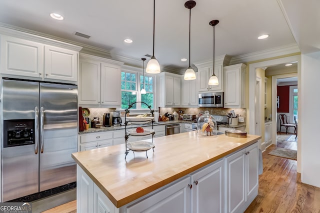 kitchen featuring visible vents, white cabinets, butcher block countertops, ornamental molding, and stainless steel appliances