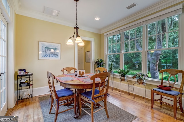 dining space featuring light wood finished floors, baseboards, visible vents, and ornamental molding