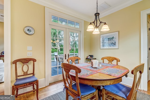 dining area with a chandelier, wood finished floors, baseboards, french doors, and crown molding