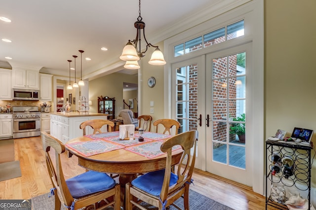 dining area with ornamental molding, recessed lighting, french doors, and light wood-style flooring