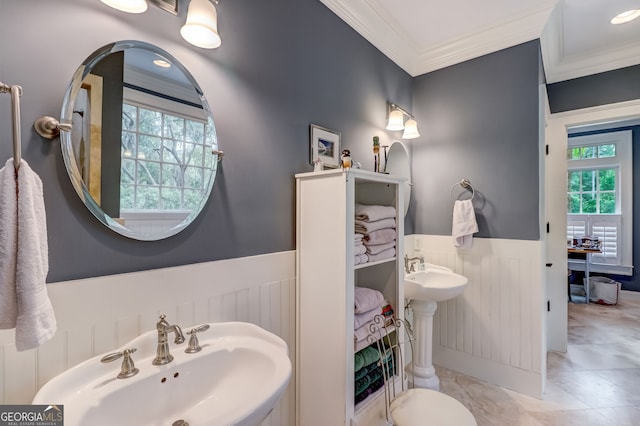 bathroom featuring a wainscoted wall, a sink, and crown molding