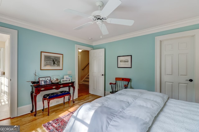 bedroom with baseboards, light wood-style flooring, a ceiling fan, and crown molding