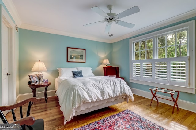 bedroom with wood finished floors, a ceiling fan, baseboards, visible vents, and crown molding