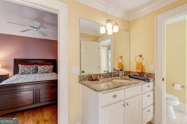 ensuite bathroom with toilet, ceiling fan, ensuite bathroom, crown molding, and vanity