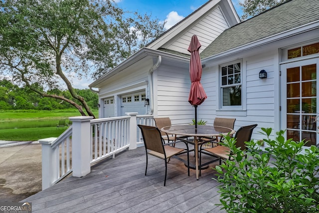 wooden deck with a garage and outdoor dining space