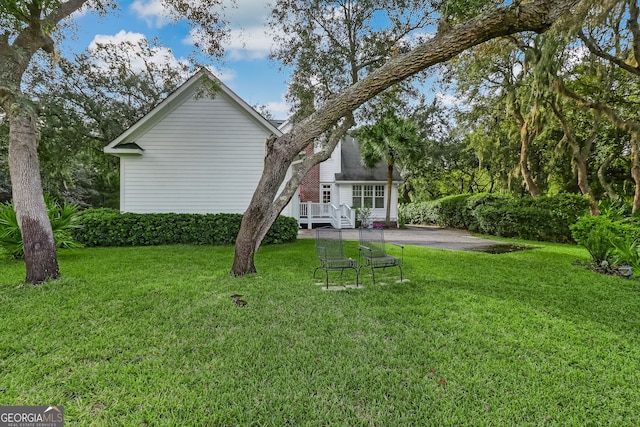 back of house with aphalt driveway and a lawn