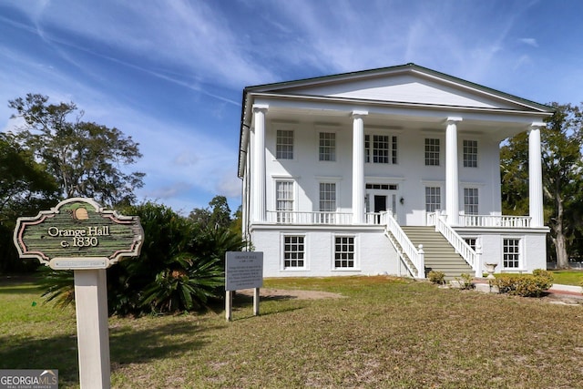 greek revival inspired property with stairs, covered porch, and a front yard