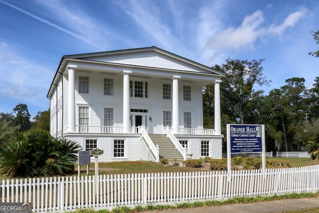 neoclassical / greek revival house with a porch, stairway, and a fenced front yard