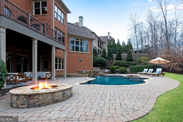 pool featuring an outdoor fire pit and a patio