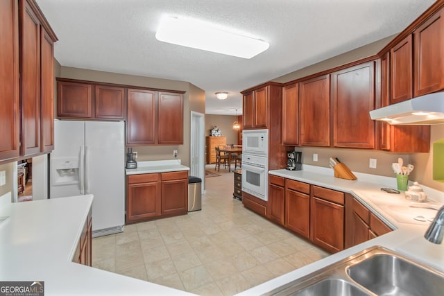 kitchen with a textured ceiling, light countertops, and white appliances