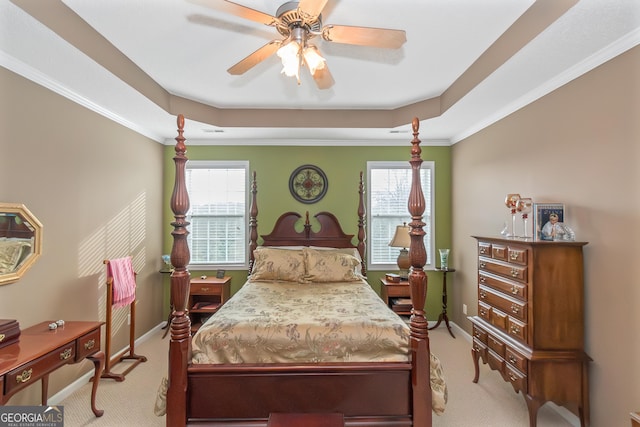 carpeted bedroom with a ceiling fan, a tray ceiling, multiple windows, and baseboards