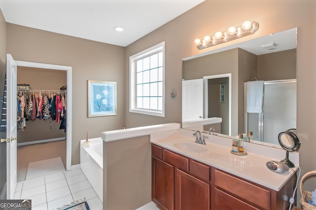 bathroom with a garden tub, tile patterned flooring, vanity, a stall shower, and a walk in closet