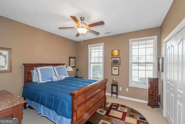 bedroom with a closet, visible vents, a ceiling fan, light carpet, and baseboards