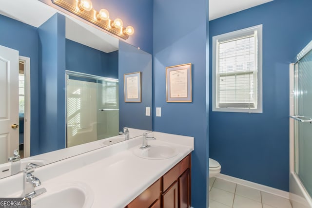 bathroom featuring a shower with shower door, a sink, baseboards, and tile patterned floors