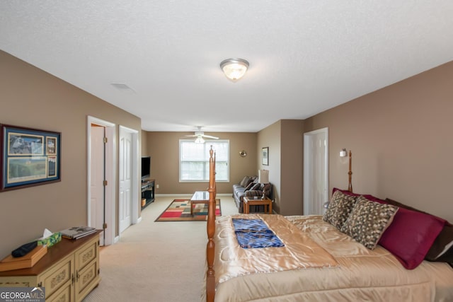 bedroom with baseboards, a textured ceiling, and light colored carpet