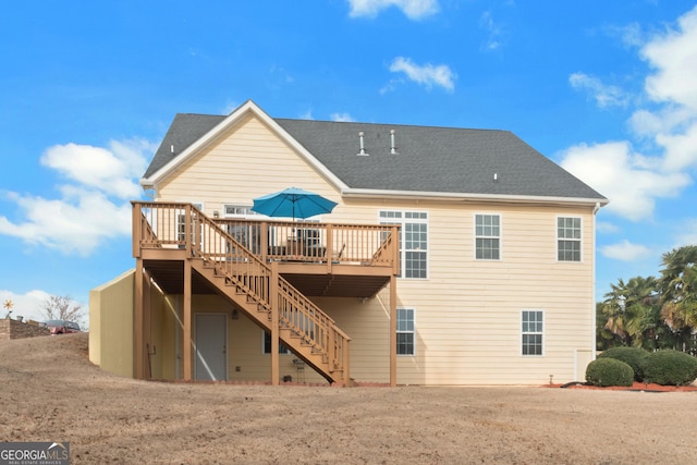 rear view of property with roof with shingles, stairway, and a wooden deck