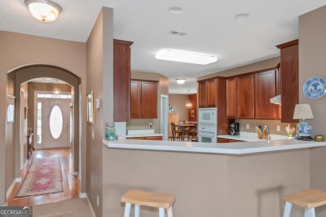 kitchen with arched walkways, light countertops, white appliances, and visible vents