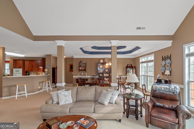 living room with decorative columns, visible vents, and light colored carpet