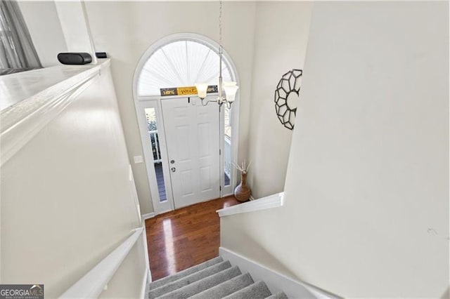 foyer entrance featuring stairs, wood finished floors, and an inviting chandelier