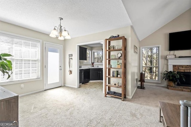 interior space with lofted ceiling, light carpet, a fireplace, and a textured ceiling