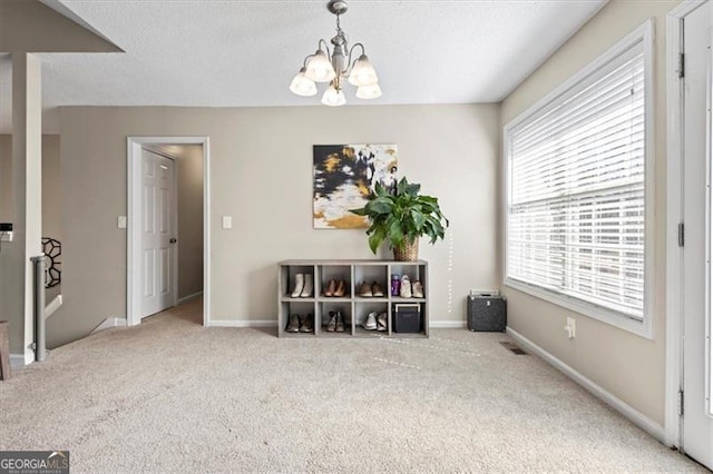 interior space with carpet floors, baseboards, a chandelier, and a textured ceiling