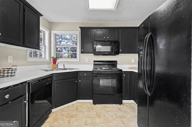 kitchen with a sink, black appliances, light countertops, and dark cabinets