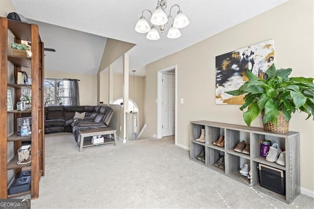 carpeted living room featuring baseboards and a notable chandelier