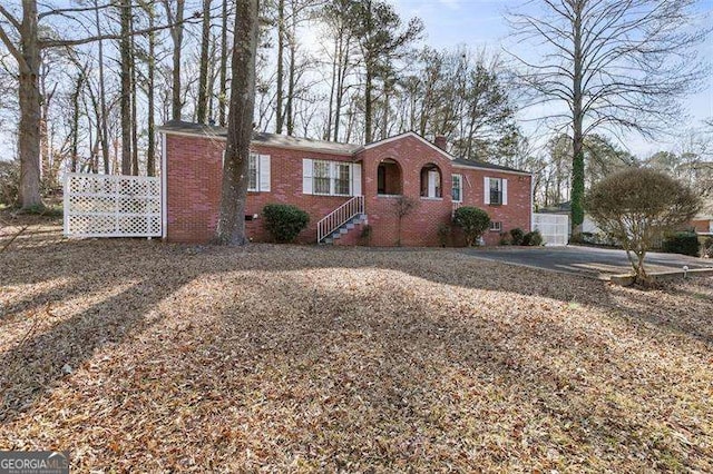 single story home featuring brick siding, crawl space, a chimney, and fence