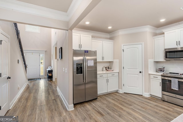 kitchen featuring appliances with stainless steel finishes, light wood-style floors, white cabinetry, and crown molding