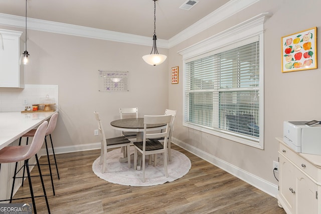 dining room featuring ornamental molding, wood finished floors, visible vents, and baseboards