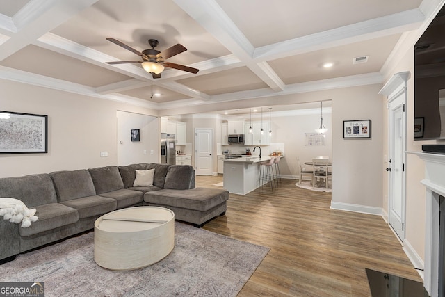 living room with beamed ceiling, coffered ceiling, wood finished floors, and visible vents