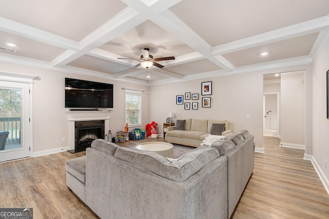 living area featuring baseboards, visible vents, a fireplace, and light wood finished floors